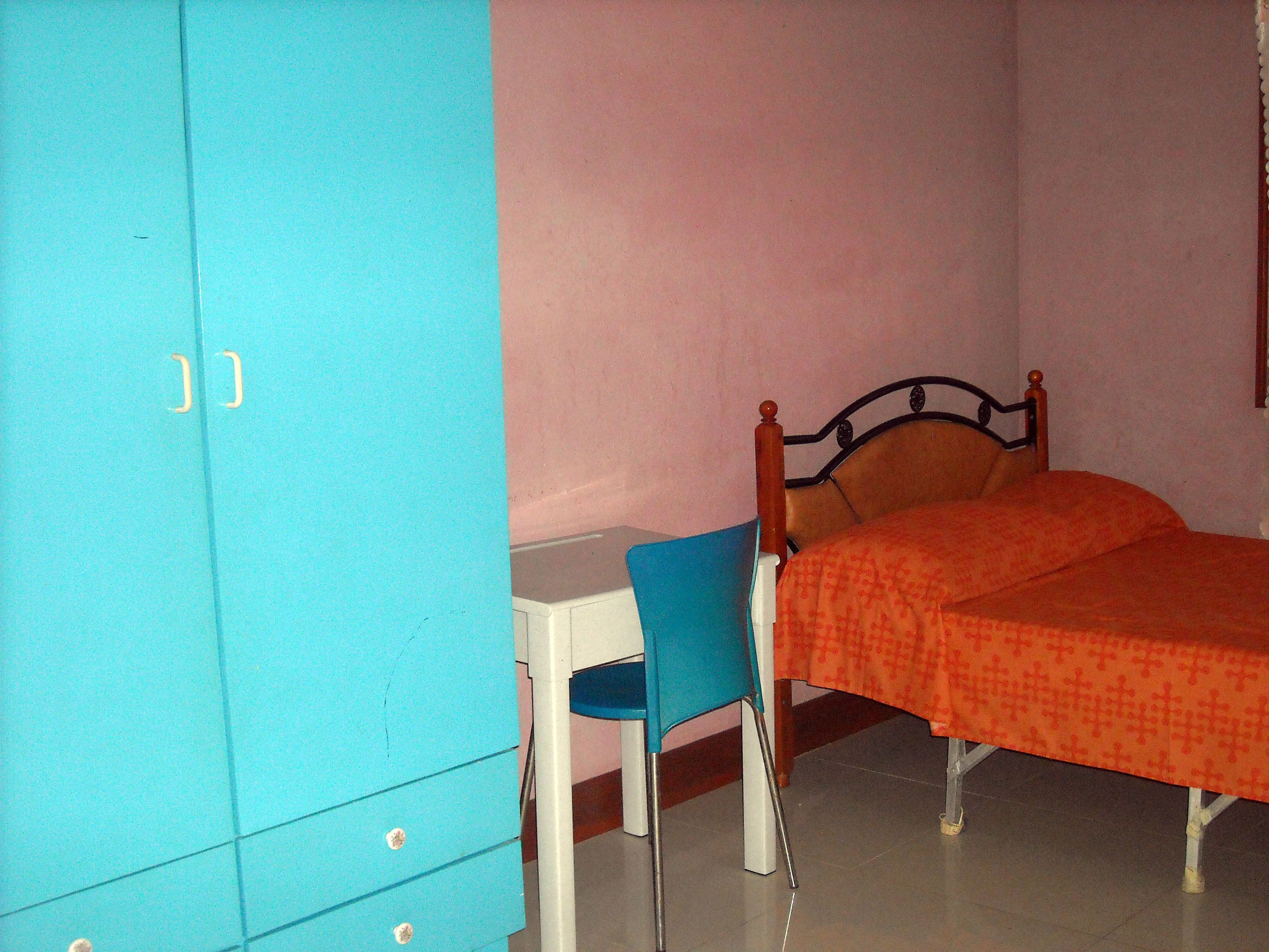 Un dormitorio con cama, escritorio y un armario azul.