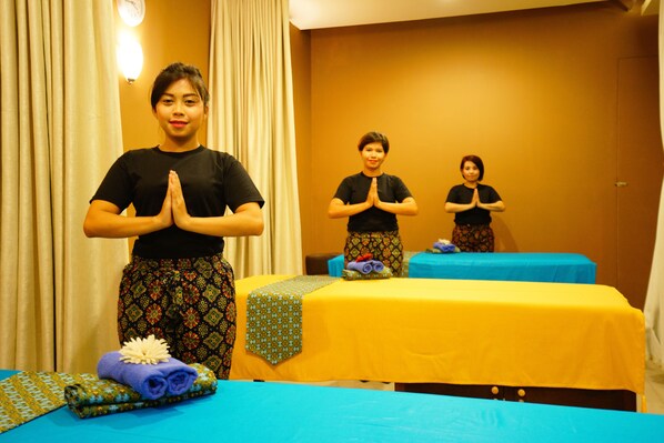 A room with two massage tables covered in blue and yellow linens, a curtain, and a wall clock. - Meize Hotel Bandung (Bandung)