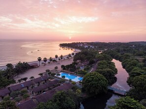 A coastal resort with a swimming pool, beach, and a river.