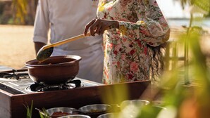 A chef preparing food outdoors with a variety of dishes and ingredients visible. - Amethyst Resort Passikudah (Pasikuda)