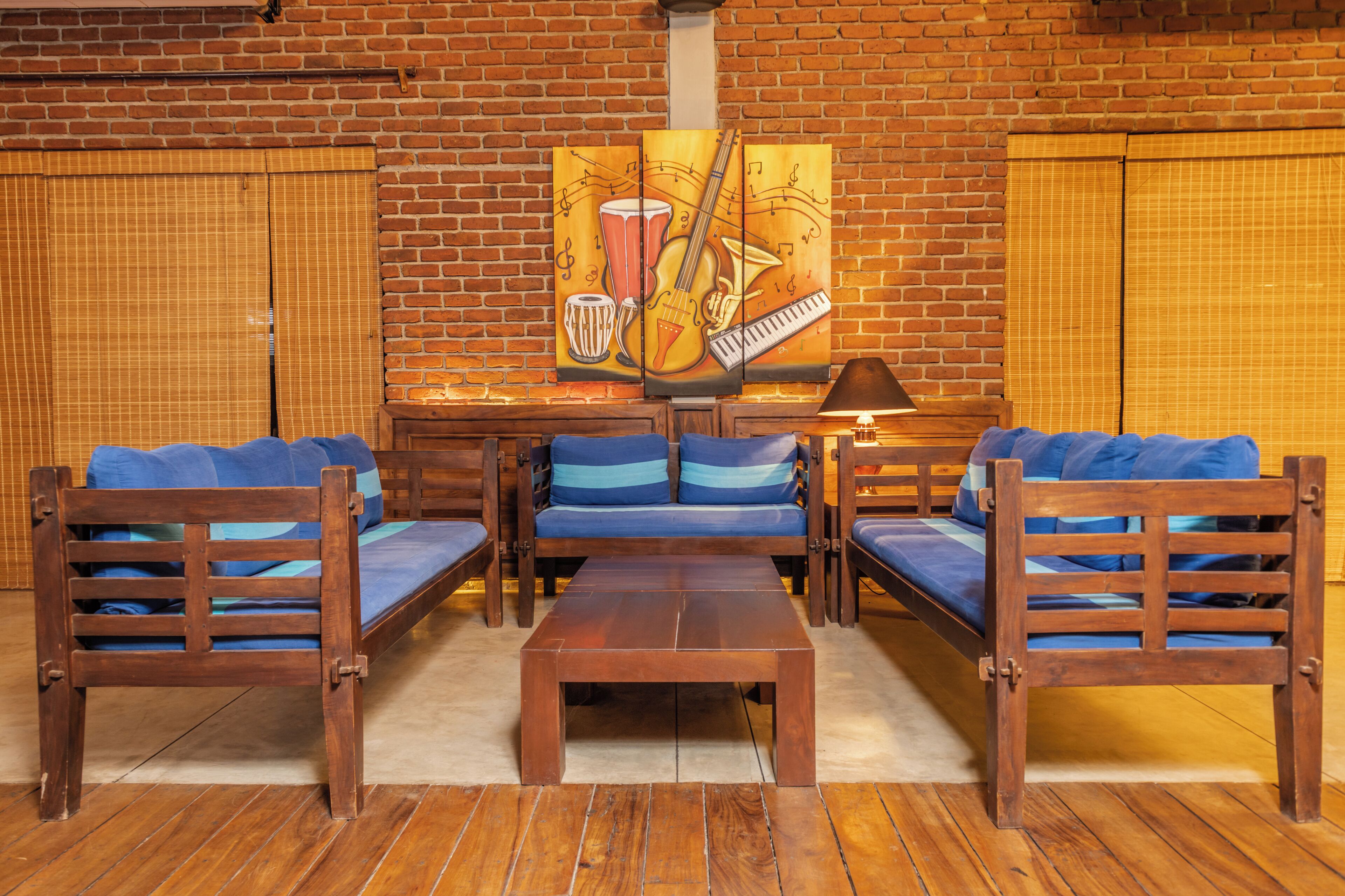 Een kamer met een bakstenen muur, een zithoek, een houten salontafel en een schilderij van muziekinstrumenten.