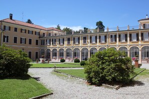 A courtyard with a building featuring arched windows and a tiled roof. - Casa Don Guanella (Ispra)
