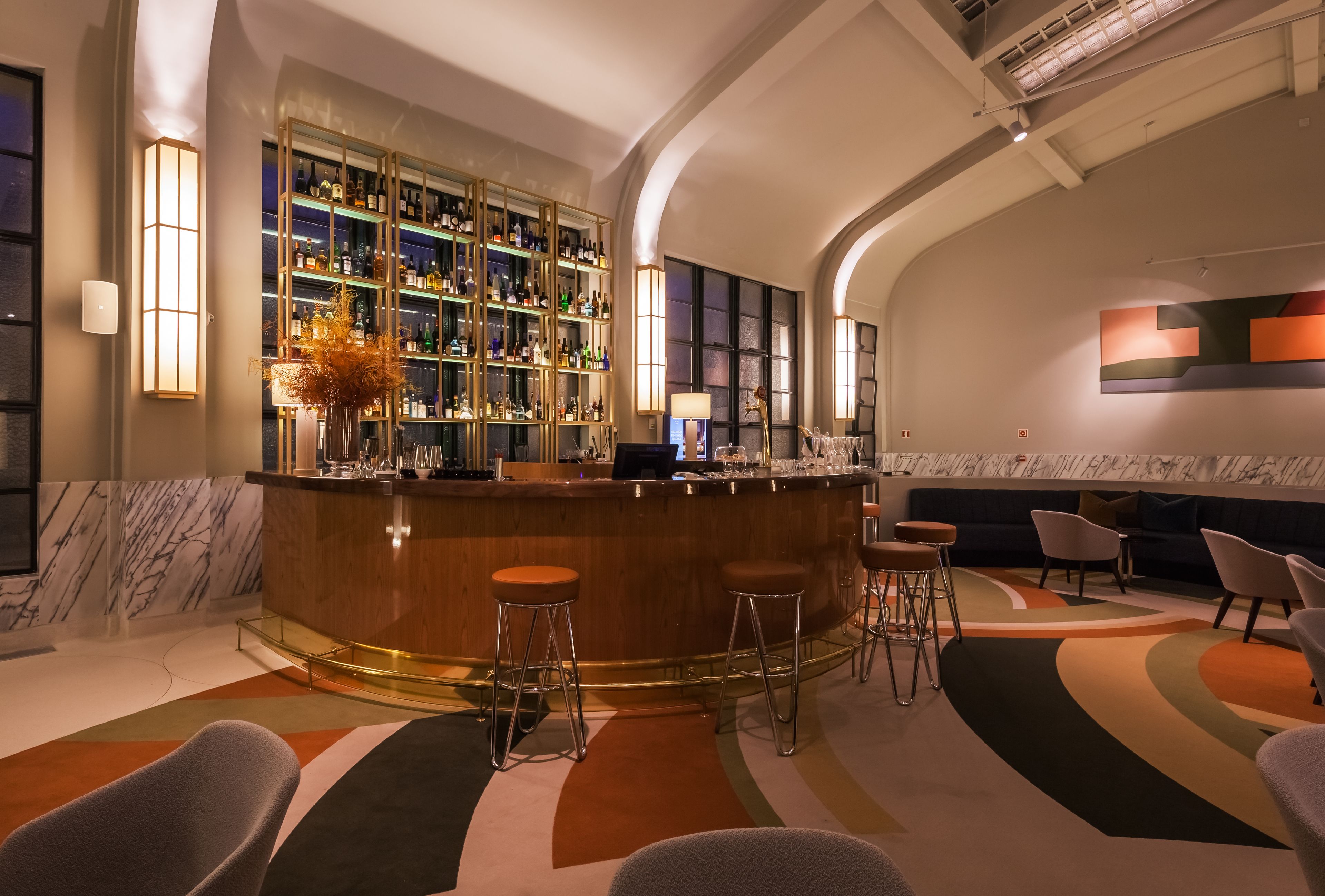 A bar area with a marble wall, a bar counter, and a variety of stools.