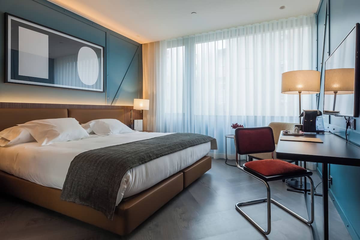Una habitación de hotel moderna con una cama grande, un escritorio y una silla.