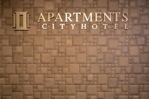 Un mur sur lequel on peut lire le texte « APARTMENTS CITYHOTEL » et un grand symbole « II ».