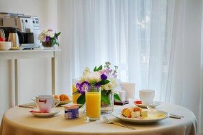 Une table de petit-déjeuner avec une tasse de café, du jus, des croissants et une assiette de nourriture.