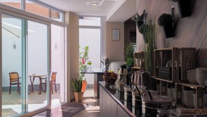 Una cocina moderna con puertas de vidrio que dan a un patio, con un juego de comedor y plantas en macetas.