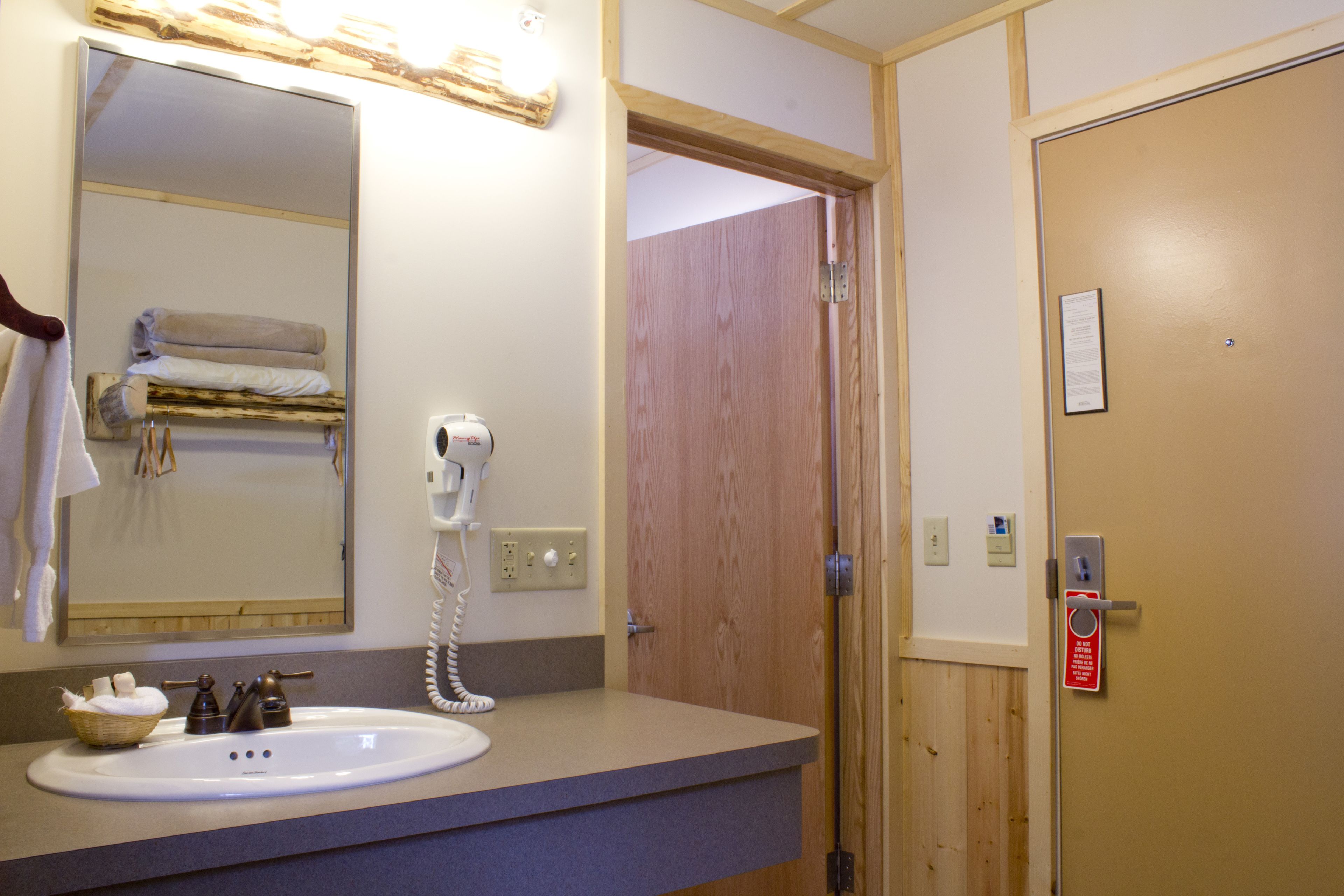 Een badkamer met een wastafel, spiegel, handdoekhouder en een haardroger.