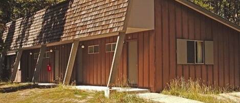 Un bâtiment en bois d’un seul étage, doté d’un toit en pente, d’un petit porche et d’une seule porte.