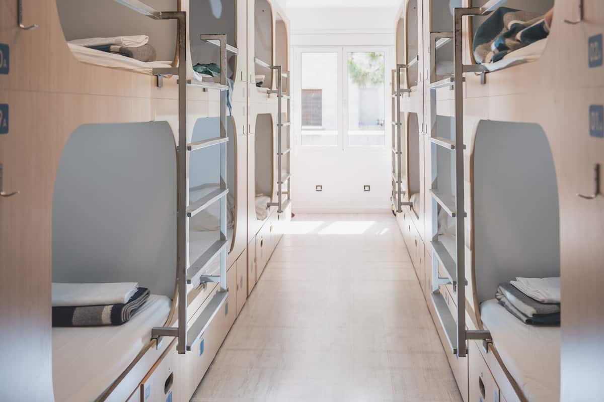 A corridor with bunk beds, lockers, and a door at the end.
