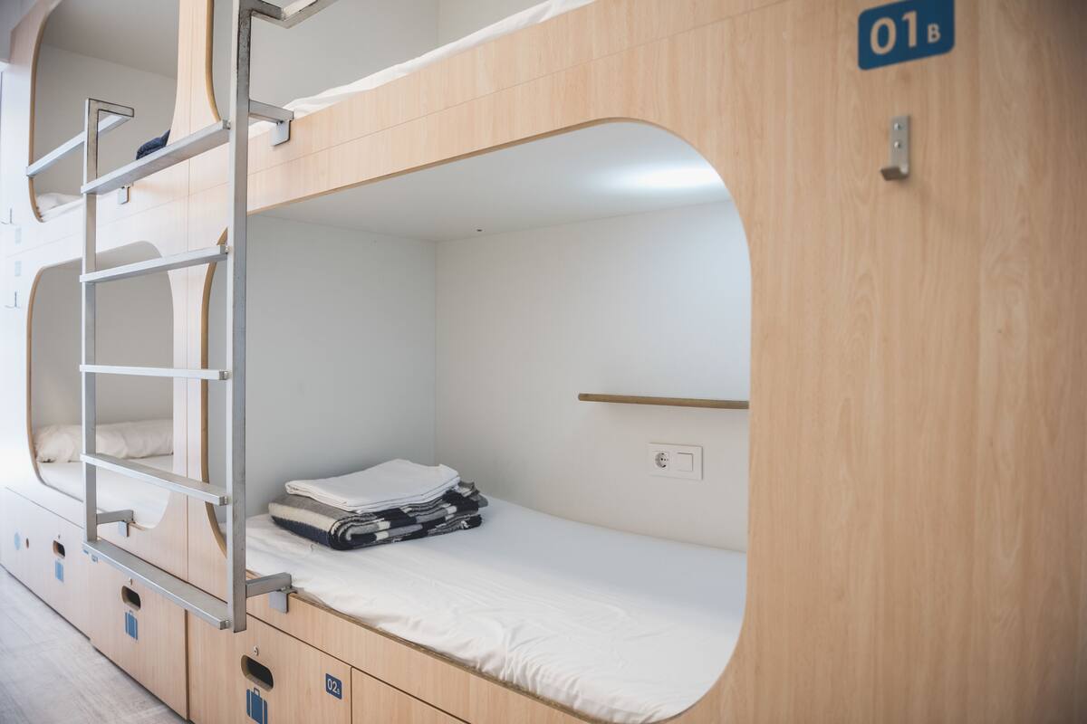 A bunk bed with a ladder, a small shelf, and a folded towel on the lower bunk.