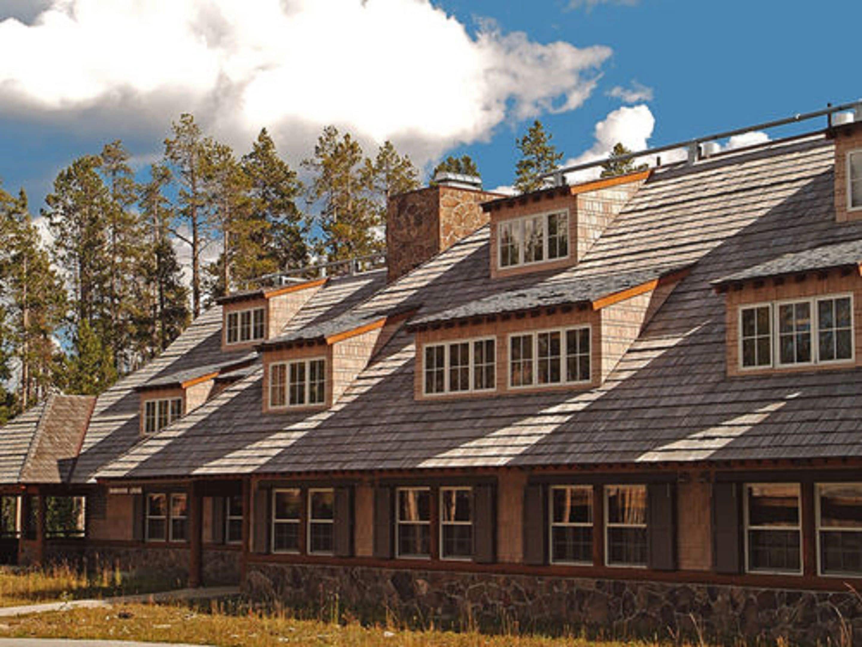 A row of log cabins with steeply pitched roofs, multiple windows, and a stone foundation.
