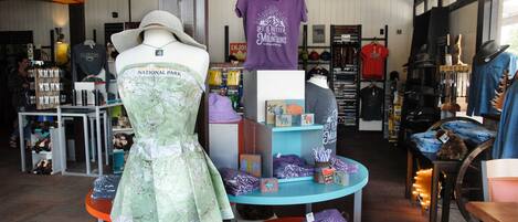 A retail store with various clothing items, including a mannequin in a green dress, a purple t-shirt, and hats.