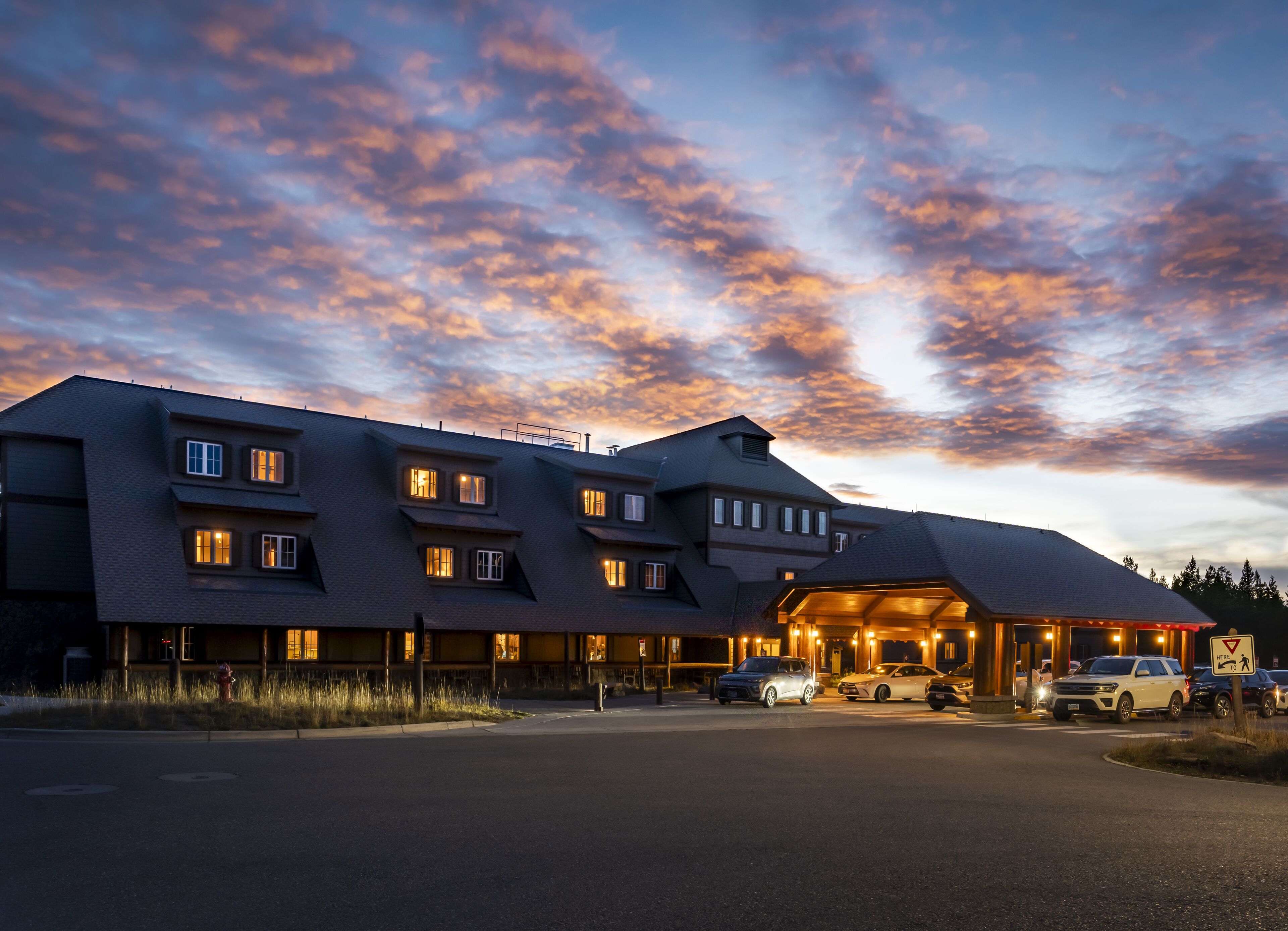 Un hotel de varios pisos con un diseño arquitectónico moderno, que cuenta con una entrada destacada con un área cubierta y múltiples ventanas iluminadas.