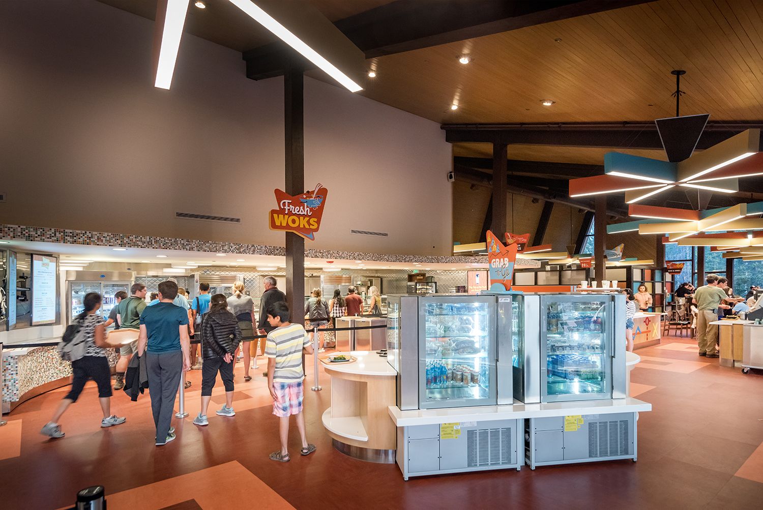 A food court with multiple counters and a 'Fresh Woks' sign.