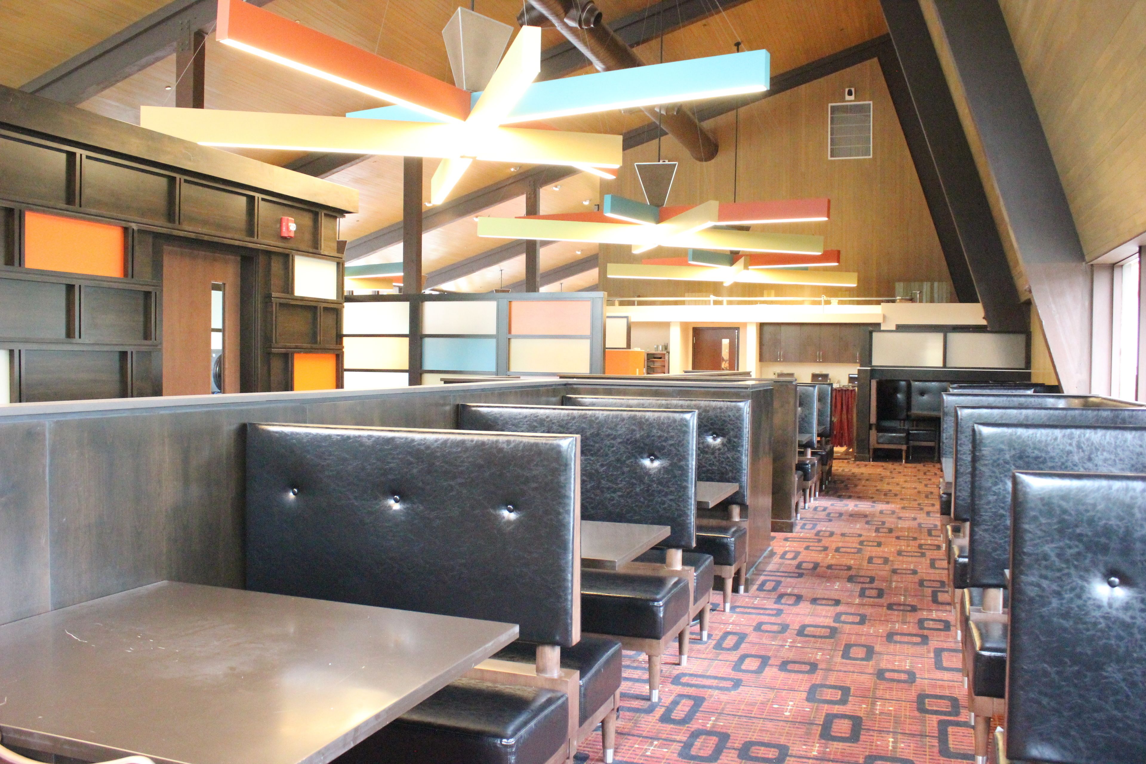A restaurant with booth seating, high ceilings, and exposed beams.