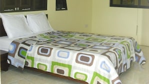 A bedroom with a bed, a window, an air conditioning unit, and a painting on the wall.