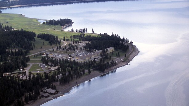 An aerial view of a coastal area with a large building complex, roads, and a body of water.