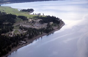 An aerial view of a coastal area with a large building complex, roads, and a body of water. - Lake Yellowstone Hotel and Cabins (Yellowstone National Park)