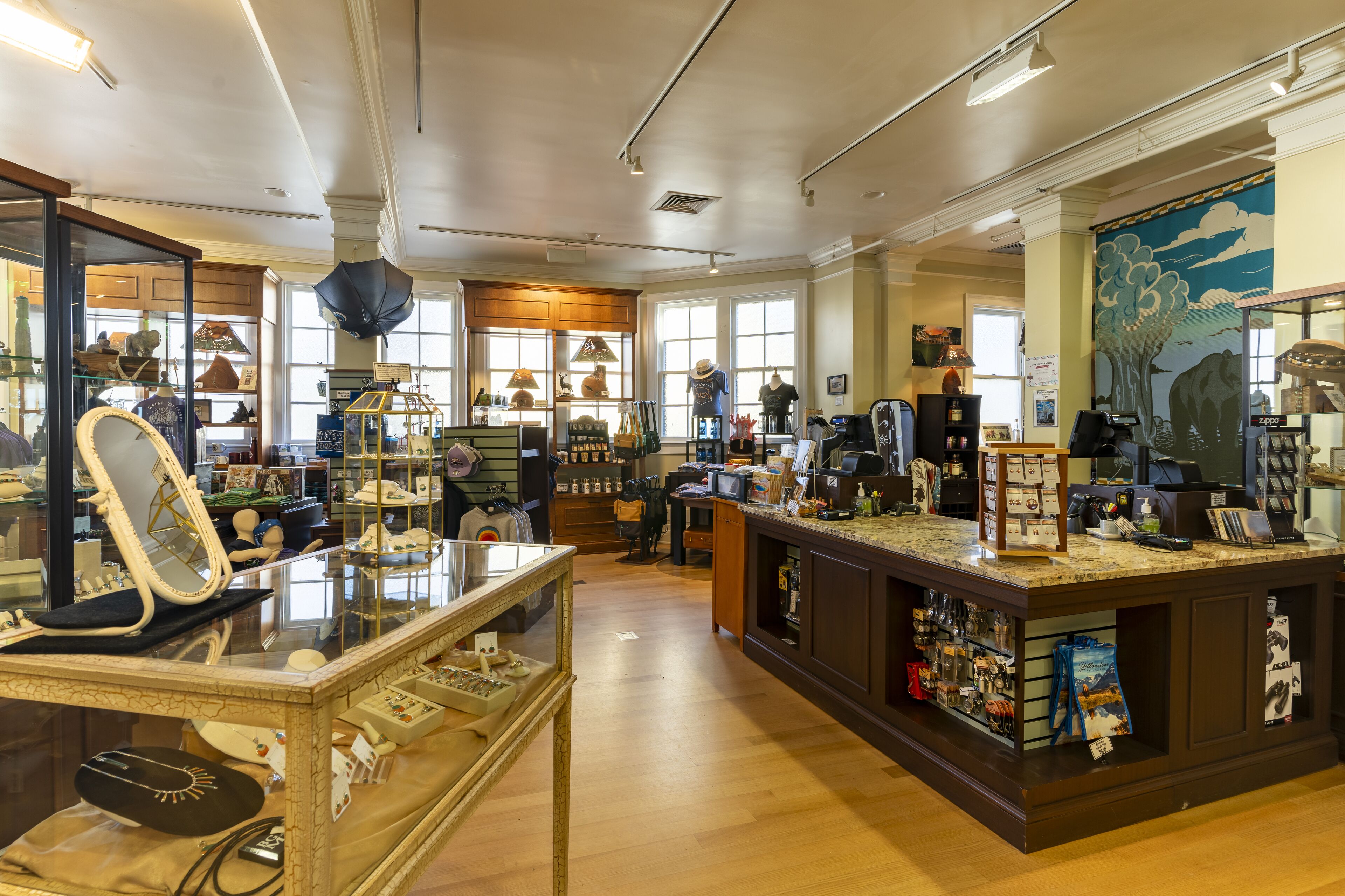 A spacious boutique hotel lobby with a central bar area, wooden flooring, and large windows allowing natural light.
