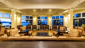 A spacious room with a large table and chairs, large windows offering a view of the water, and a cozy seating area with a sofa.