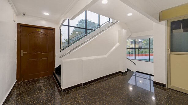 Un intérieur moderne avec un sol en marbre, une porte en bois, un escalier en verre et une vue dégagée grâce à de grandes fenêtres.