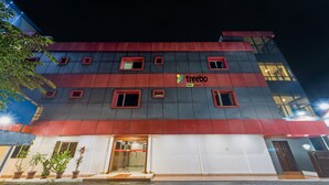 Un immeuble à plusieurs étages, doté d’une façade rouge et grise, de nombreuses fenêtres et d’une enseigne sur laquelle on peut lire « Treebo ».
