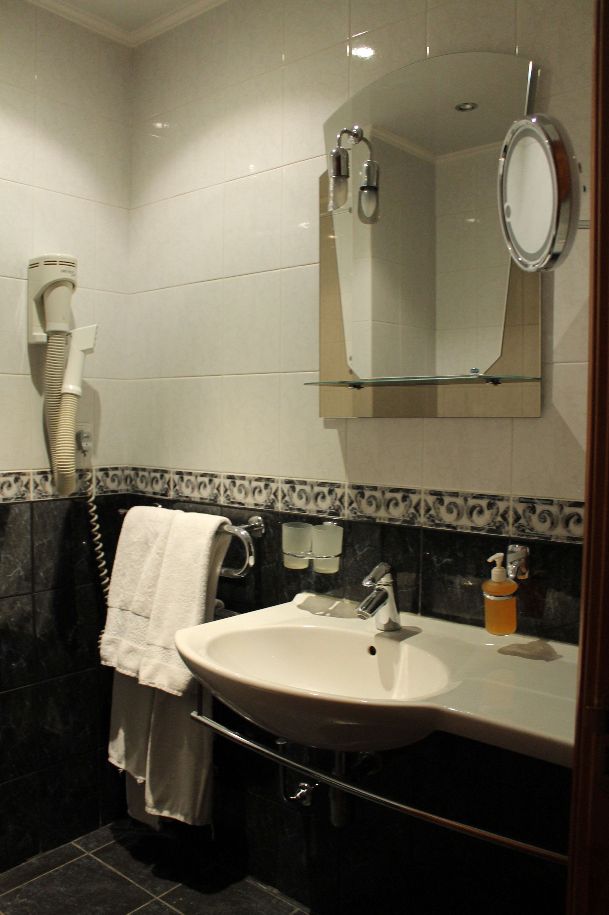 A bathroom with a sink, mirror, towel rack, and hairdryer.