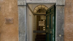 Una entrada con un arco de piedra, una puerta verde y un letrero que dice "DOMVS LIBERA".