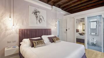 A modern bedroom with a large bed, a headboard, bedside tables, and a wall-mounted artwork.