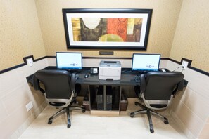 A dual-monitor workstation with two chairs, a printer, and a framed abstract painting on the wall. - Best Western Plus Drayton Valley (Drayton Valley)