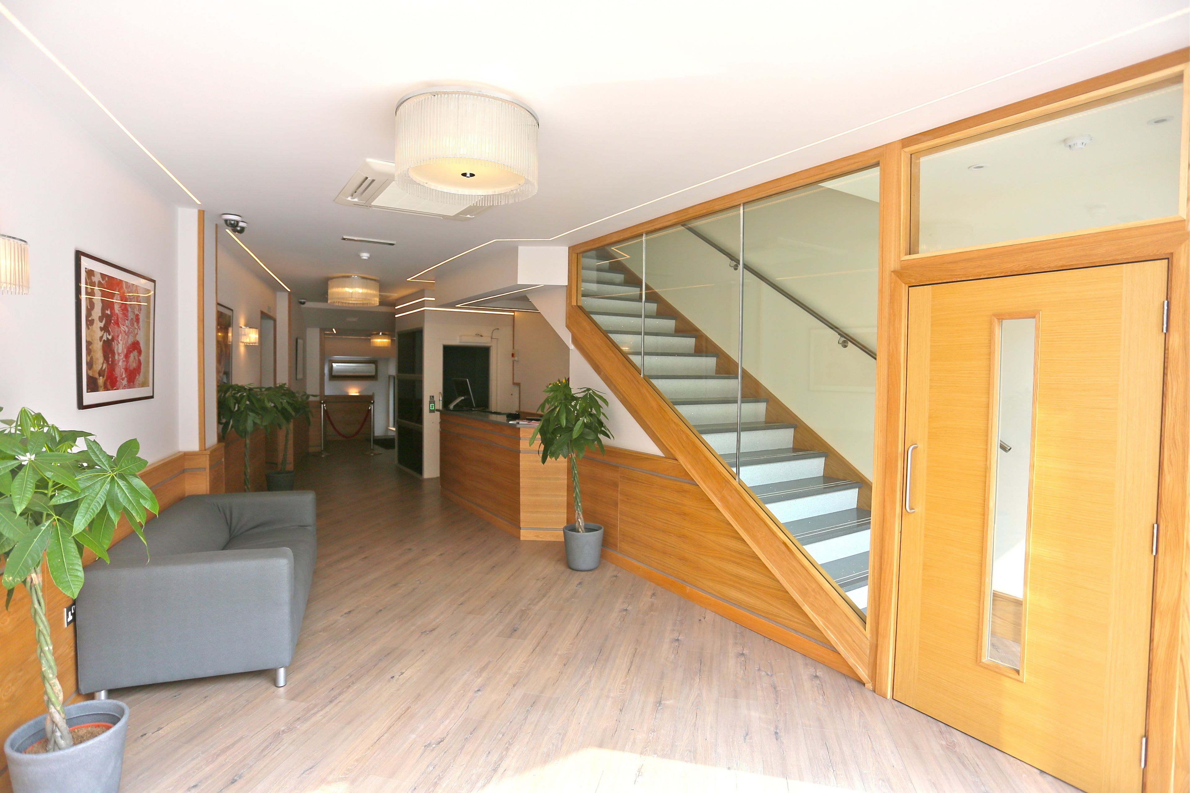 A modern interior with a staircase, wooden flooring, and a reception desk.