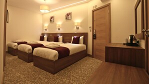 A hotel room with a large bed, two bedside tables, a wooden wardrobe, and a small desk with a kettle. - London Kings Hotel (London)