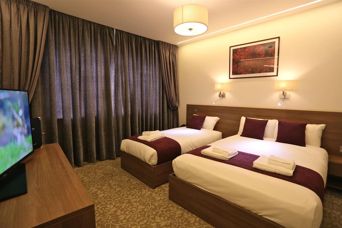 A hotel room with two beds, a TV, and a painting on the wall.