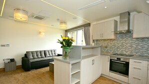 A modern kitchen with light wood cabinets, a built-in oven, and a grey countertop. - London Kings Hotel (London)