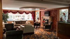 Eine Hotelhalle mit Sitzgelegenheit, Kamin und Fernseher.