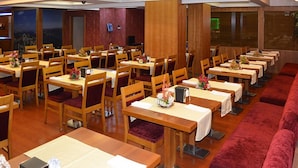 Ein Restaurant mit mehreren Holztischen und -stühlen, die in Reihen angeordnet sind.