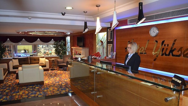 Eine Hotelhalle mit einer Rezeption, einer Sitzecke und einer großen Uhr an der Wand.