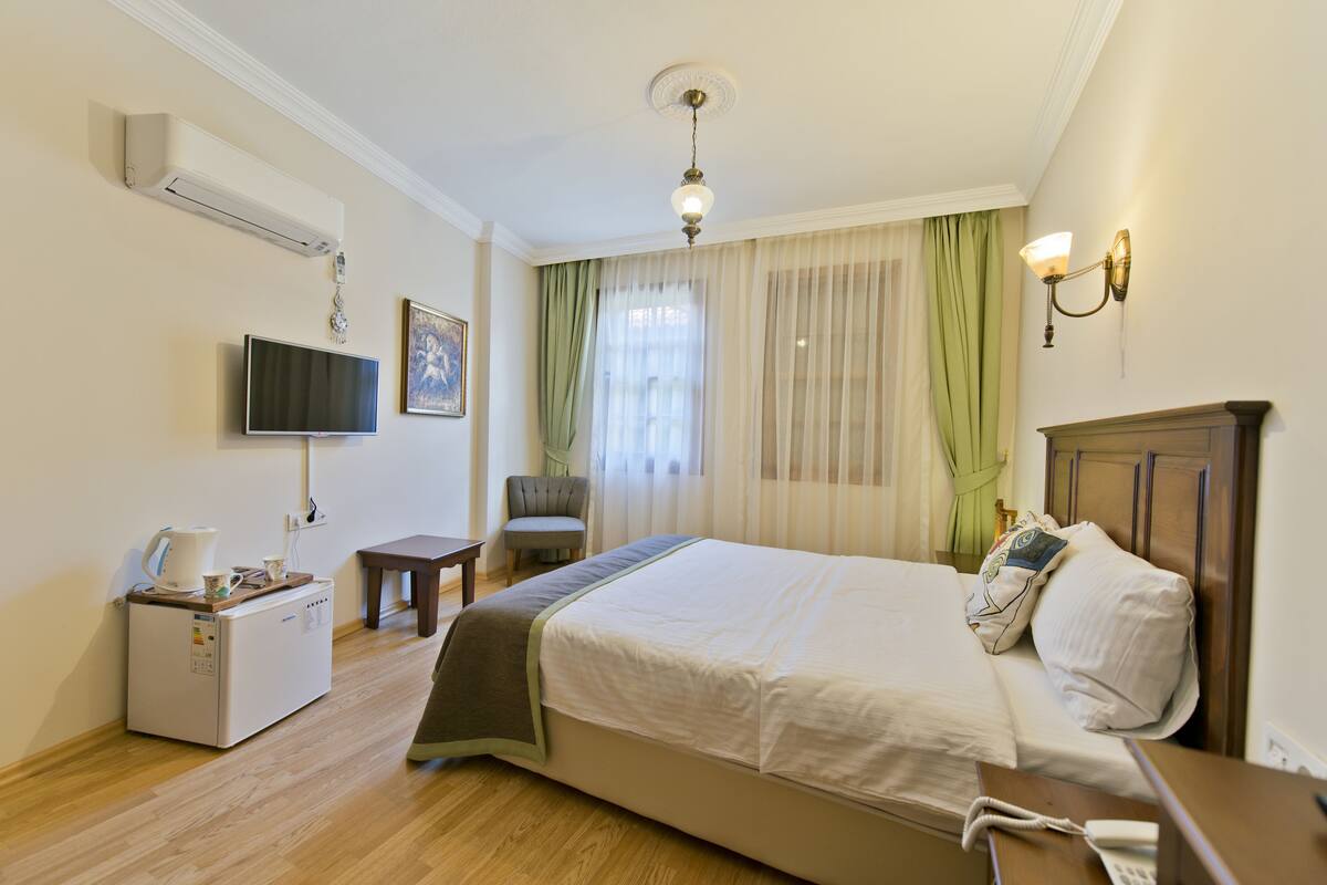 A hotel room with a bed, a television, a desk, a chair, and a coffee machine.