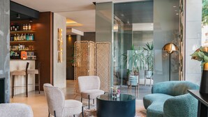 A modern living room with a round coffee table, two armchairs, a sofa, a bookshelf, and a glass partition. - Vincci Mercat Hotel (Valencia)