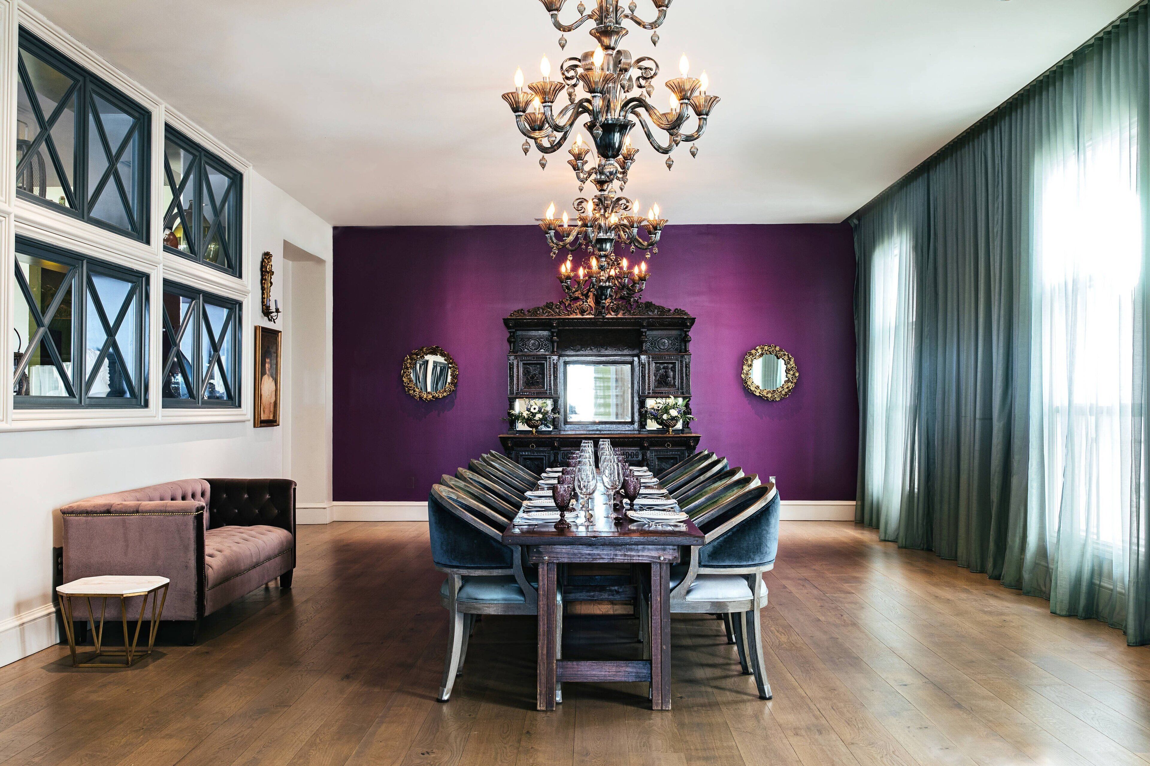 A dining room with a large wooden table, blue upholstered chairs, and a chandelier.
