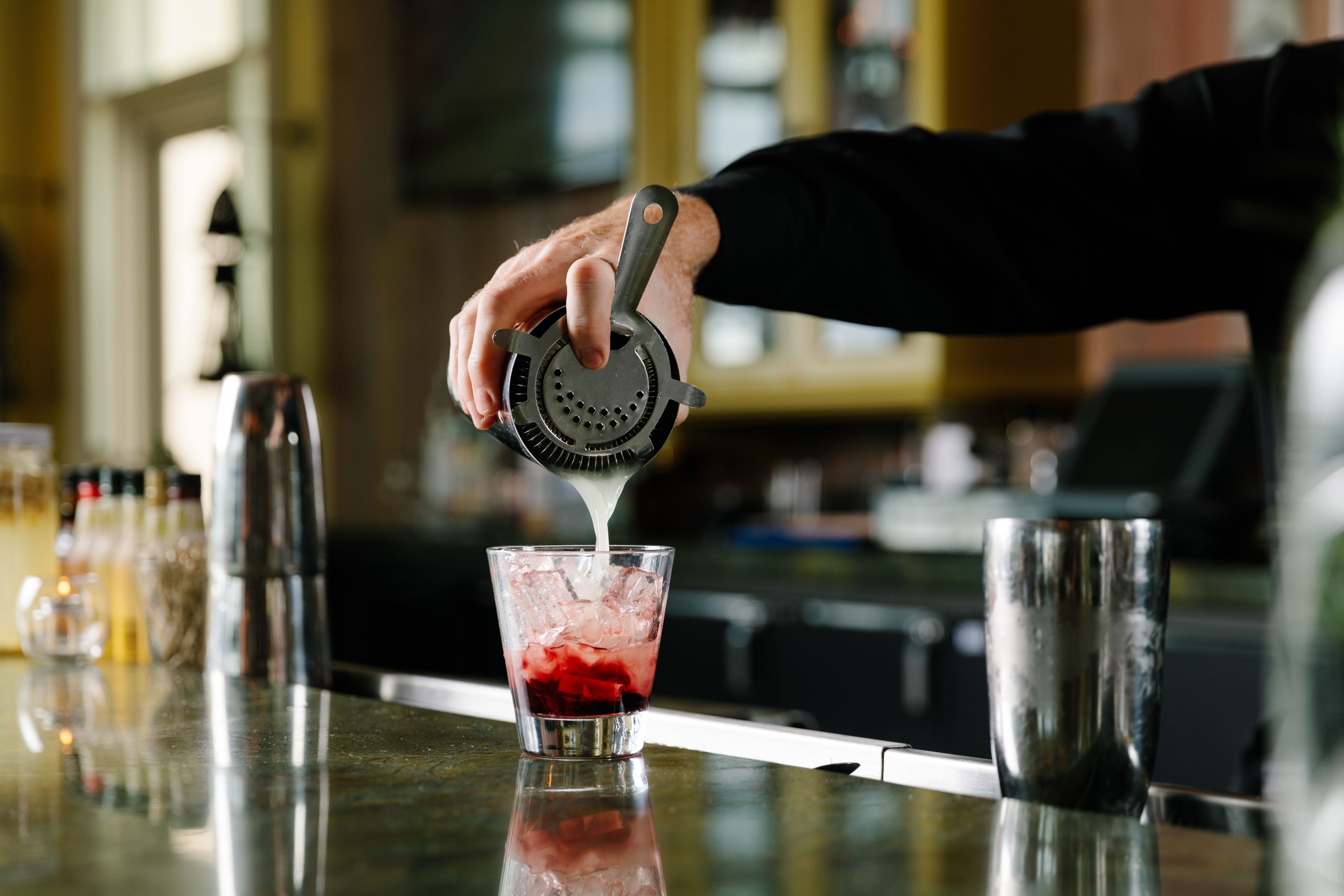 Una persona serviendo una bebida en un vaso en un bar.