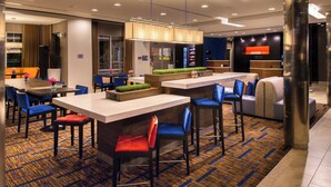 Un hall d’hôtel moderne comprenant un comptoir d’accueil, des espaces de détente et un bar.