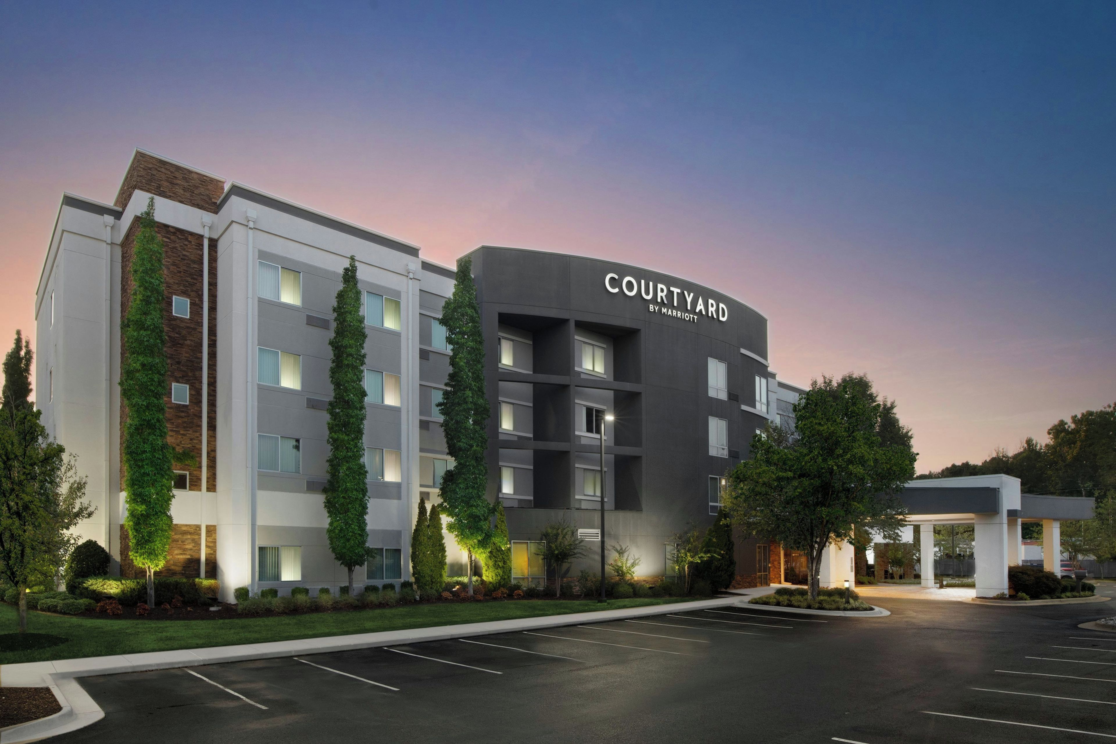 A Courtyard by Marriott hotel with a modern design, multiple floors, and a parking lot.