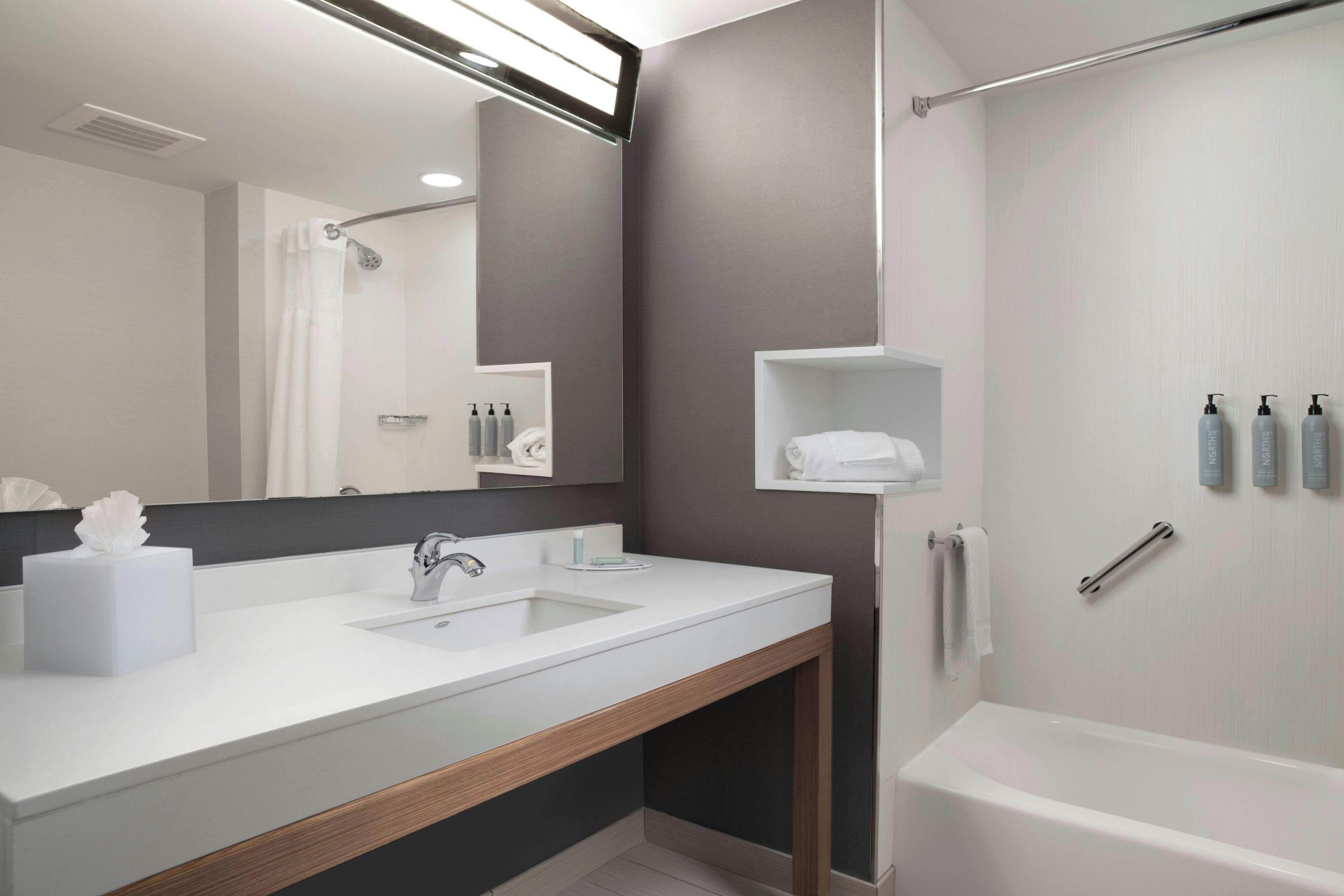 Un baño moderno con un espejo grande, dos lavamanos, ducha y bañera.