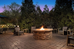 An outdoor seating area with stone fire pit, chairs, and tables. - Courtyard Hot Springs (Hot Springs)