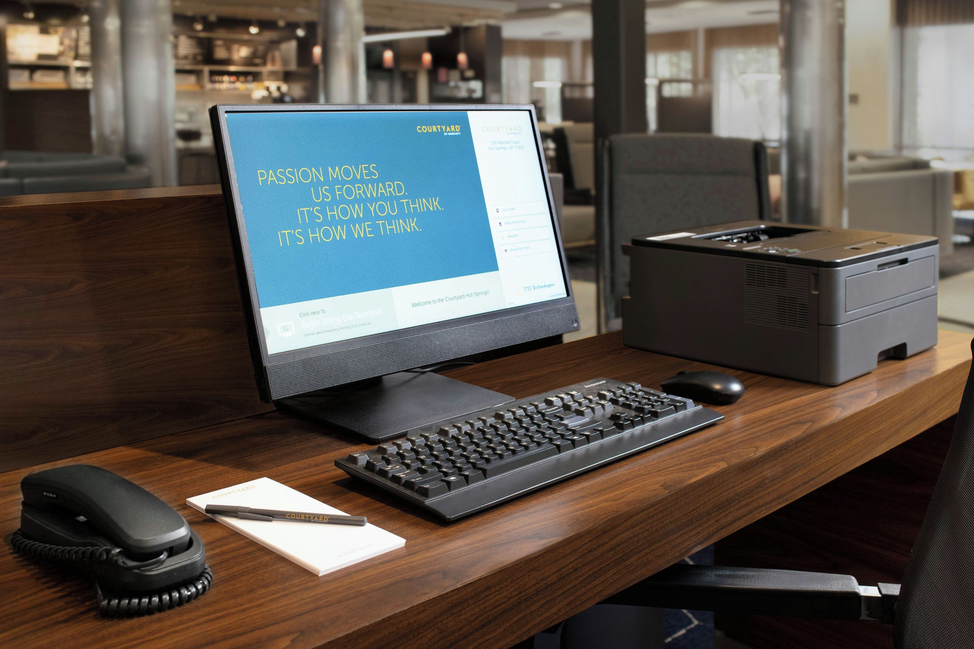 A hotel workspace with a computer, keyboard, mouse, and telephone.