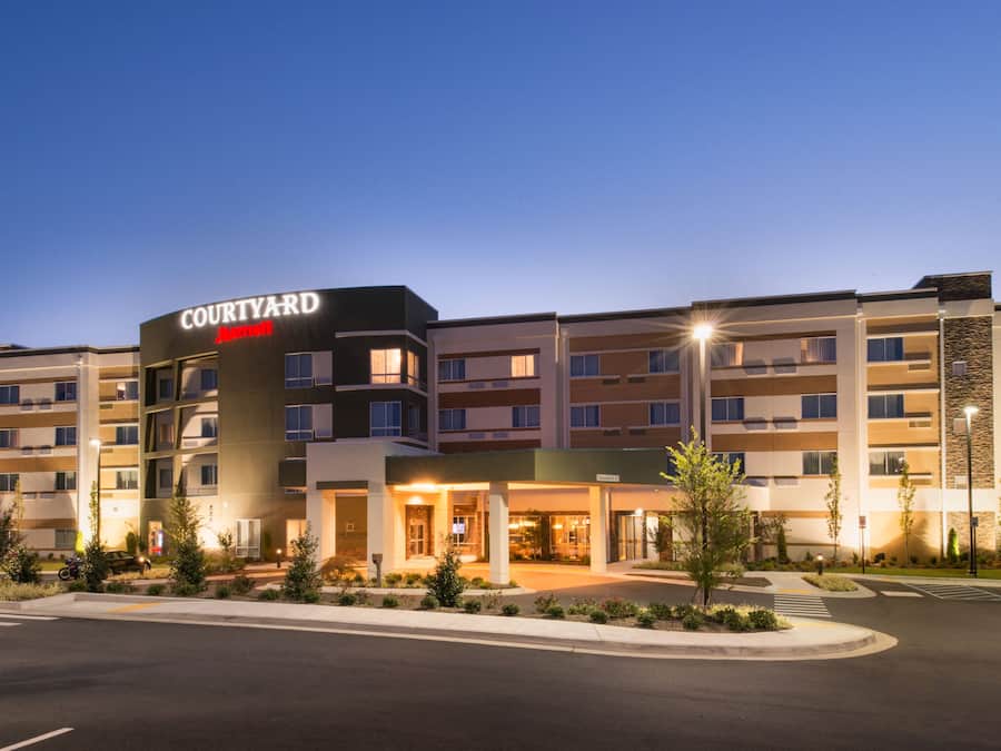 A Courtyard by Marriott hotel with a modern design, multiple floors, and a well-lit entrance.