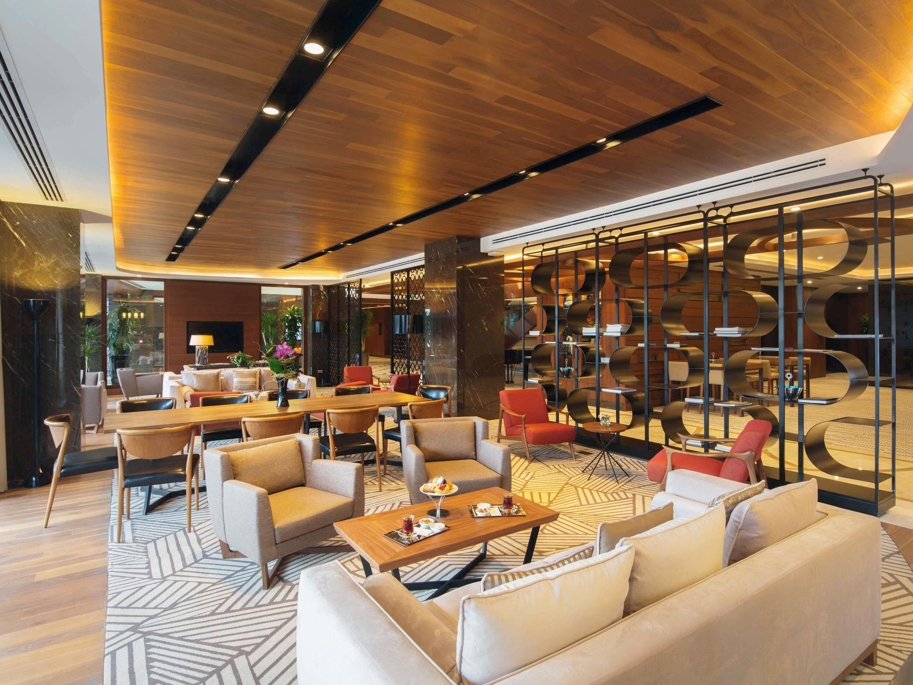 A modern hotel lobby with a central seating area, a TV, and a decorative wall with circular patterns.