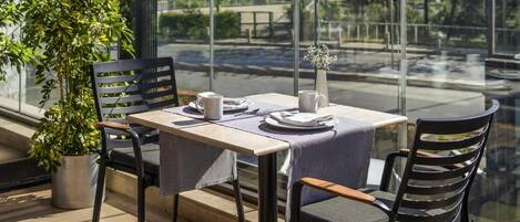Una mesa de comedor con sillas, una planta en maceta y vistas a un puente y follaje.